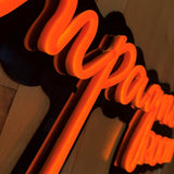 LED-neonskilt detalj: «ROOM» oransje lys på sort skilt.